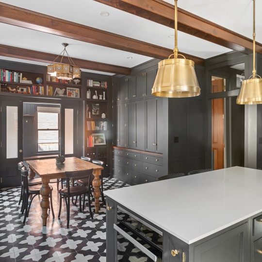 Kitchen with dark built-in cabinetry, a large white island, brass pendants, and patterned tile flooring.